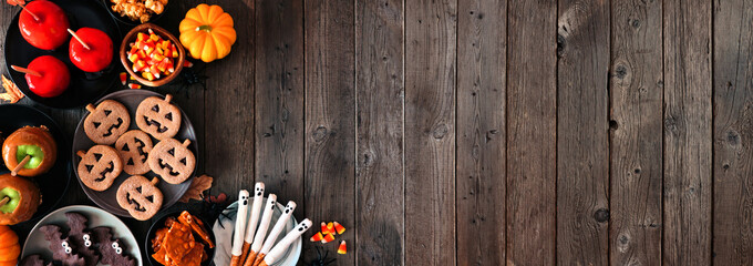 Rustic Halloween treat corner border over a dark wood banner background with copy space. Top view....