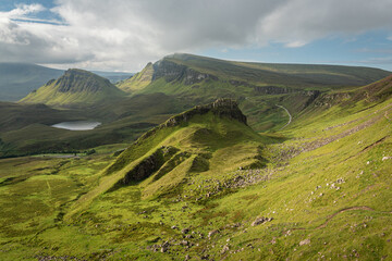 Scenic view of rock formations in Quiraing, Isle of Skye, Scotland. Beautiful area of grassy mountains covered by blooming heather in summer, hidden lochs and steep cliffs