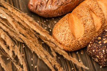 fresh baked bread loaves with spikelets on wooden surface