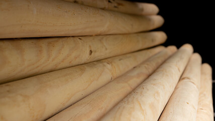 Wooden pillars used for gardening lay assorted on a rack. The pillars have a pointy side that make them easy to push down in the soil.
