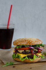 juicy powerful burger with beef and vegetables on a bun with sesame seeds.