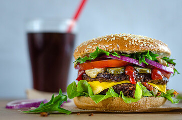 juicy powerful burger with beef and vegetables on a bun with sesame seeds.