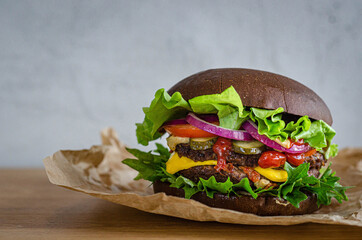 juicy powerful burger with beef and vegetables on a rye bun.