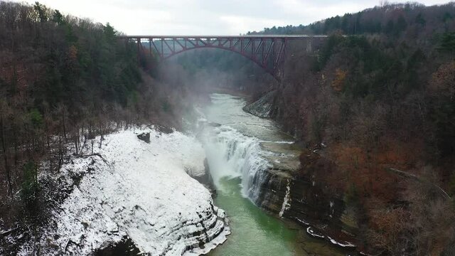 Aerial view of a waterfall under a bridge in the winter with snow and mist in New York