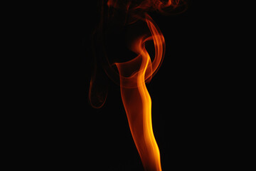 Orange smoke on a black background. Colored smoke. Smoke illuminated by orange light. Bizarre spellbinding flames.