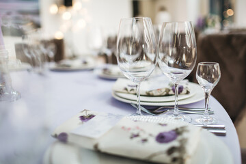 Wine glasses on the decorated table for the wedding celebration, cutlery and plates for the...