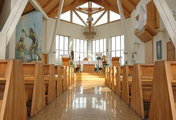 Modern empty catholic church interior brightly illuminated with natural window light