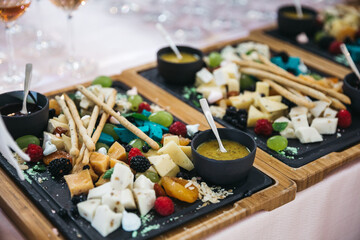 Table catering with cheese set, variety of cheeses on the party buffet, parmesan, dor blue, blue cheese, brie, berries and sauces on the wooden tray, wedding snack bar