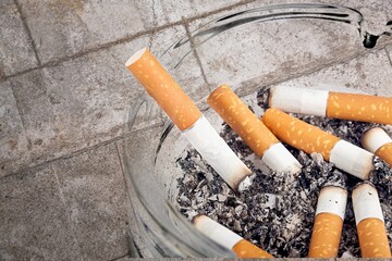 Ashtray and smoked cigarettes with smoke on desk