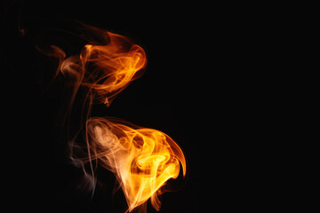 Orange smoke on a black background. Colored smoke. Smoke illuminated by orange light. Bizarre spellbinding flames.