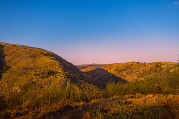 Fototapeta premium View over the mountain with the horizon in blue and orange tones.
