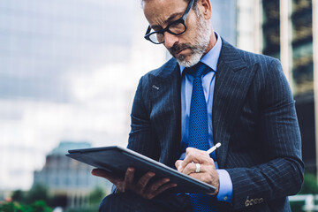 Bearded businessman looking away while holding tablet with stylus