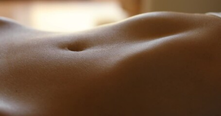 Breathing female stomach in a bed, macro video