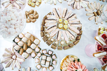 Top view of table catering with delicious desserts, macarons and candy pops. Complicated french patisserie recipes. Yummy restaurant sweet bar for prom. Concept of baking afters for formal occasions.