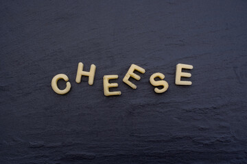 "Cheese" written out of cheese. Letters cut out of cheese. Food art, edible decoration.