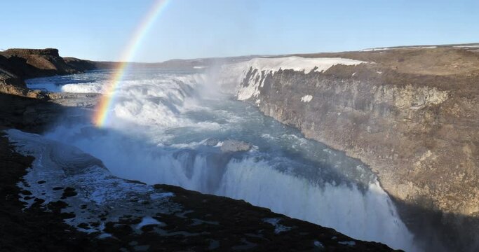 Rainbow over scenic Gullfoss waterfall Iceland wide shot morning light