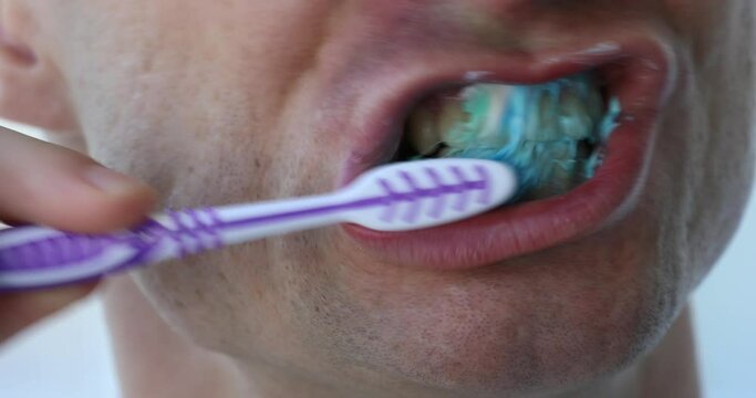 Man brushing his teeth with toothpaste, closeup