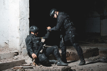 Ranger in black uniform helping to the comrade. Help in battle concept.
