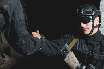 Ranger in black uniform helping to the comrade. Help in battle concept. Selective focus.