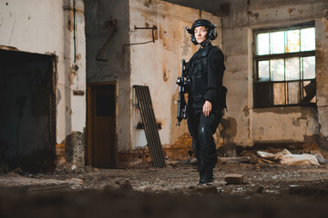 Fototapeta na wymiar Portrait of young woman soldier in black uniform with an assault rifle.
