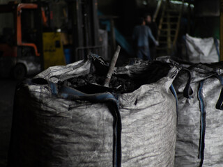 Cloth fleecy white agricultural bags with coal, inside a shovel, coal factory