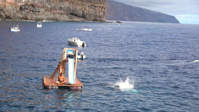 A young man jumping off the diving board of the cove of the Puerto de Puntagorda, island of La Palma, Canary Islands. Spain