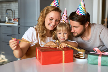 happy parents unpacking birthday gifts of their lovely daughter, congratulate and celebrate. at...