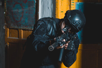 Special forces soldier in black uniform aiming with a rifle