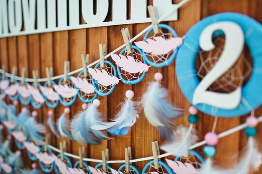 Close up of number two and tiny dream catchers in dim pink and blue colors. Beautiful interior details on trendy gender party. Charming handmade design elements. Concept of decoration and celebration.
