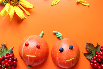 Funny pumpkin men on an orange background with Rowan branches, a place for text-the concept of a rich autumn harvest and fun holidays