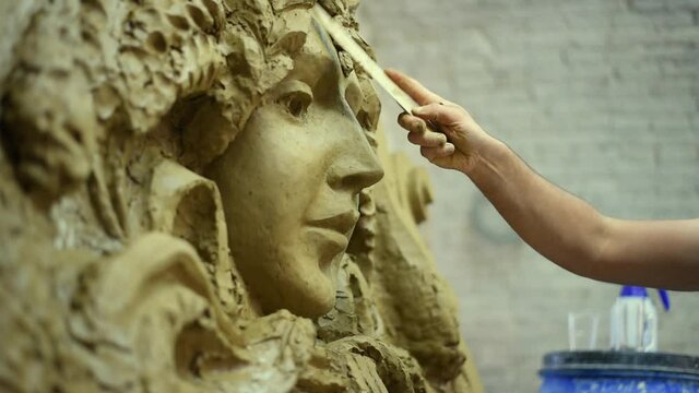 Sculptor create clay model of a mascaron ornament in restoration workshop