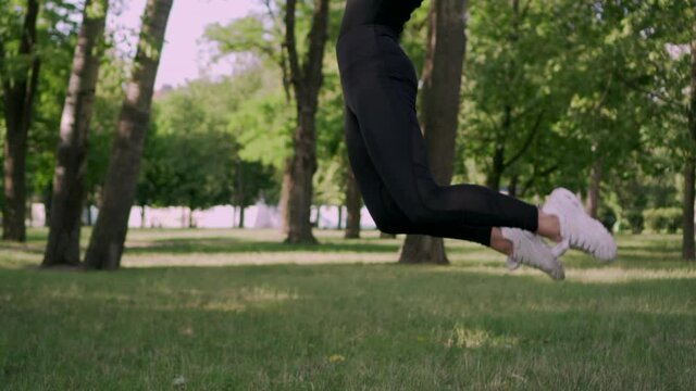 Young woman gymnast jumping in twine on in the park, slow motion. Steadicam shot.
