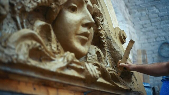 Sculptor create clay model of a mascaron ornament in restoration workshop