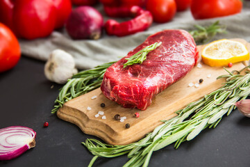 Raw beef steak on a cutting board with spices. Creative atmospheric decoration.
