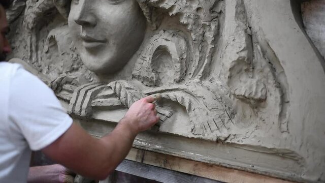 Sculptor create clay model of a mascaron ornament in restoration workshop