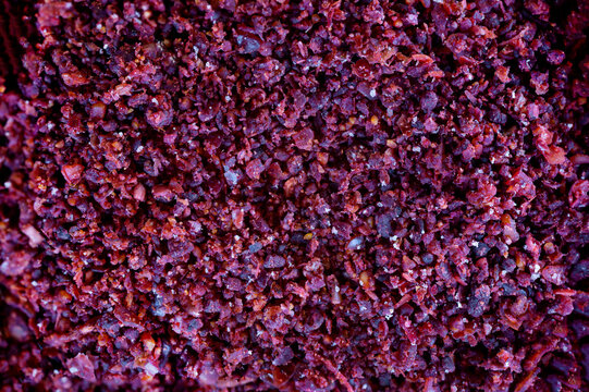 Spice Sumach is poured from a wooden spoon. Dark stone background