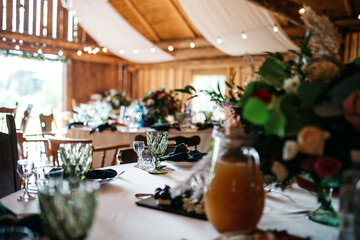 Side view of table serving with decorative floral composition and delicious food. Preparing for luxury wedding celebration in small cozy restaurant. Concept of beautiful table design and details.