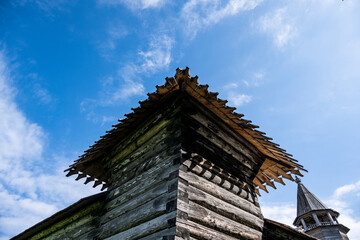 Fototapeta na wymiar vintage wooden complex with temple watchtower and fortress wall against blue sky