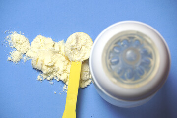 top view of baby powder milk with scoop next to a baby bottle. flat lay flat design