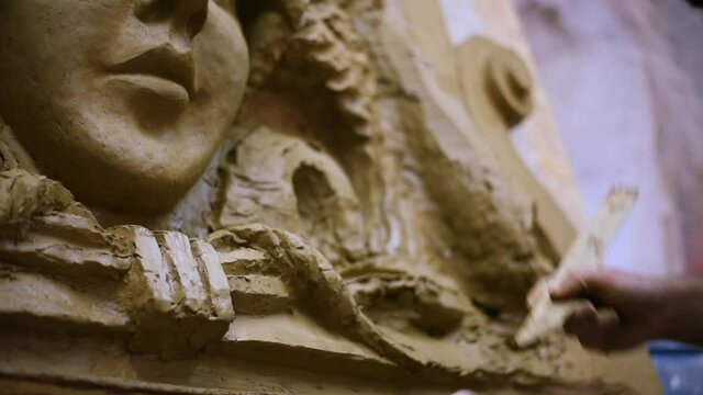 Sculptor create clay model of a mascaron ornament in restoration workshop