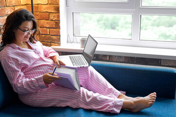 future mom working from home using laptop, caucasian female in domestic wear sit with laptop and notebook, make notes