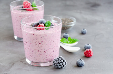 Berry smoothies of yogurt, chia seeds and frozen berries in a glass on a dark concrete background. Healthy food. Copy space.