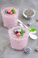 Berry smoothies of yogurt, chia seeds and frozen berries in a glass on a dark concrete background. Healthy food. Copy space.