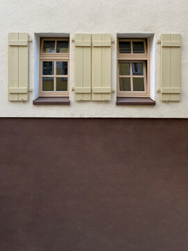 Zwei Fenster parall nebeneinander, beide mit hellgr&uuml;nen offenen Fensterl&auml;den, darunter braund Hausfassade