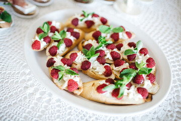 Top view of plate with sweet snack, baguette with mint leaves, raspberry, mascarpone. Delicious dish on white background looking tasty. Simple recipe for beginners. Concept of healthy dietary food.