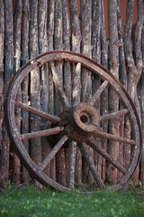 Fototapeta na wymiar Old wagon wheel leaning against a fence