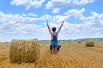 Young countrywoman enjoying time in golden wheat fields on cloudy, sunny day.