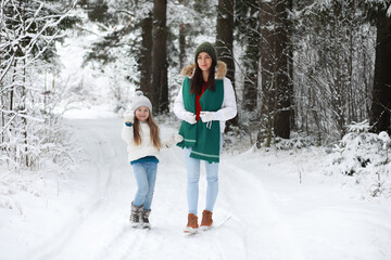 Fototapeta na wymiar Young family for a walk. Mom and daughter are walking in a winter park.