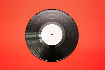 Old vinyl record on the red flat lay background.