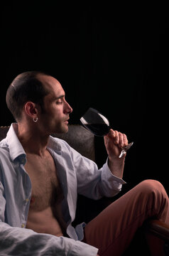Hombre sentado bebiendo una copa de vino.